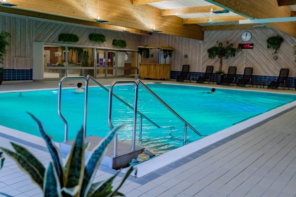 En mindre simbassäng med turkost vatten, två personer simmar lugnt.