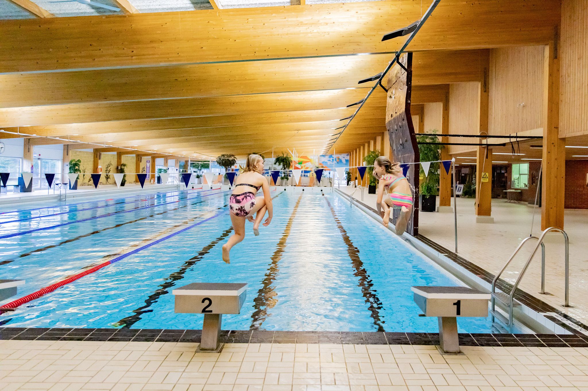 Två flickor hoppar i stora bassängen på Klitterbadet